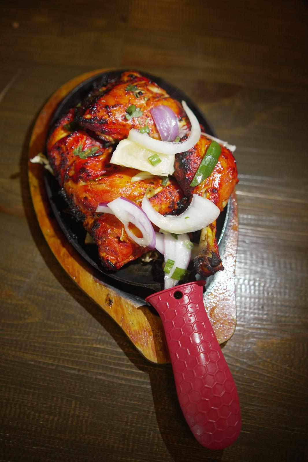 Chicken tandoori on a sizzling platter with fresh garnish